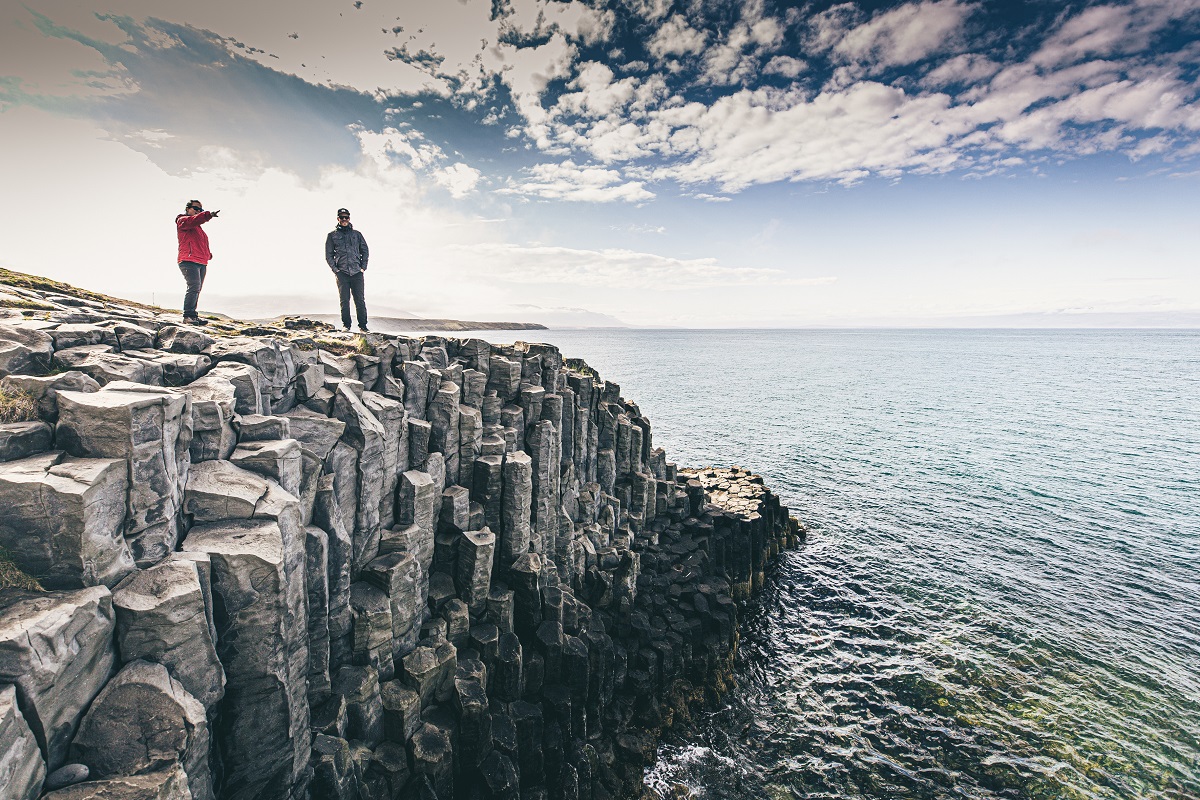 Twee mensen kijken uit over zee, vanaf de mooie basaltformaties bij Hofsos in Noord-IJsland.