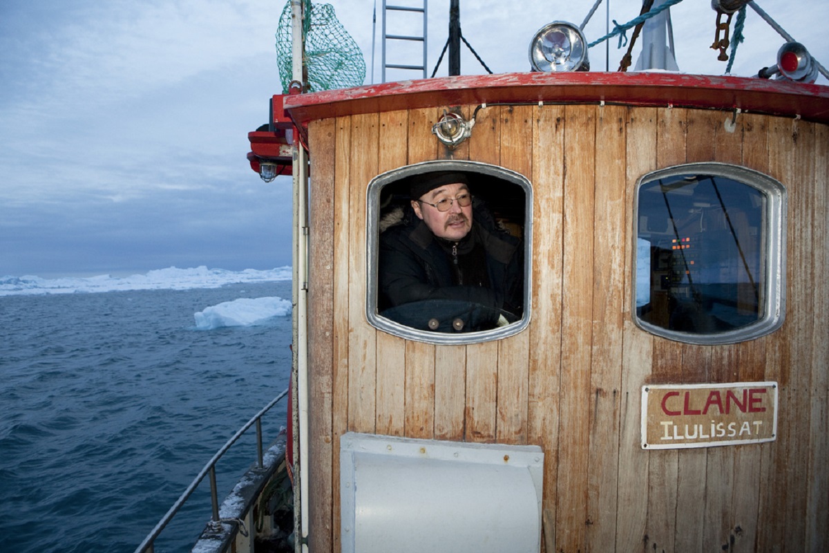 Kapitein in de kleine stuurhut van de houten boot in de fjord bij Ilulissat.