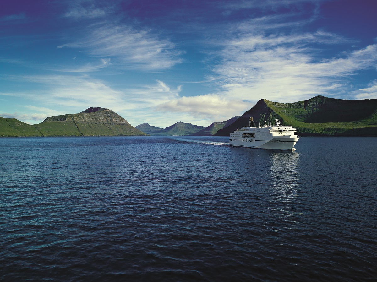 De Norrona veerboot vaart tussen de groene Faroer eilanden door.
