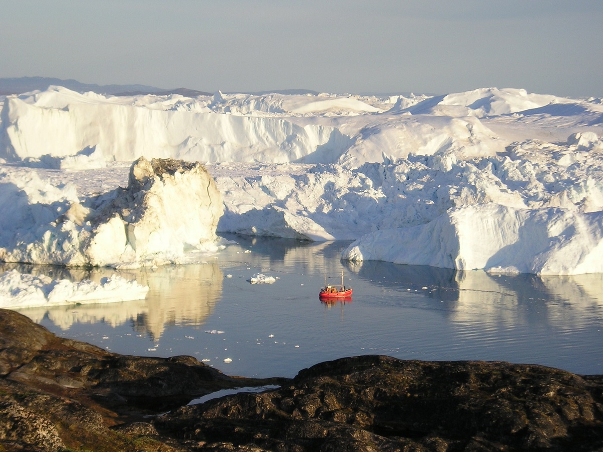 Rode zeilboot tussen enorme ijsbergen in de Disko Baai, West Groenland.