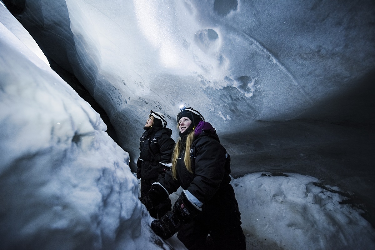 Twee reizigers kijken gefascineerd omhoog in een ijsgrot op Spitsbergen.