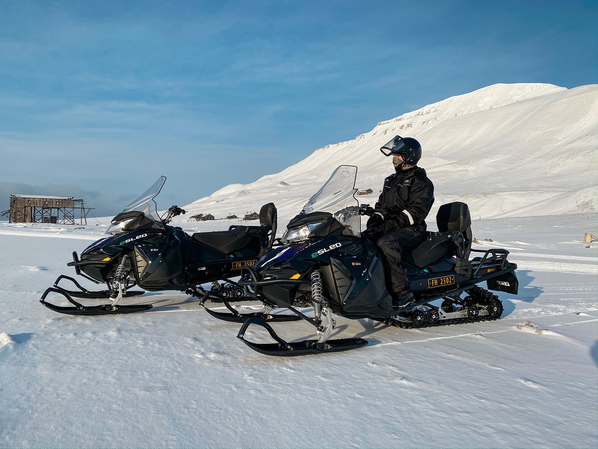 Een reiziger houdt pauze en geniet van het uitzicht tijdens een sneeuwscootertour in Spitsbergen.