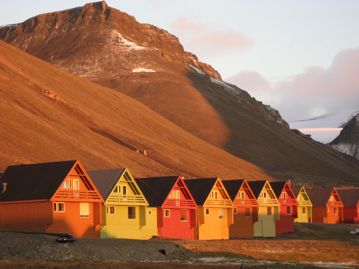 Een rij verschillend gekleurde huisjes in Longyearbyen Spitsbergen onder de middernachtszon.