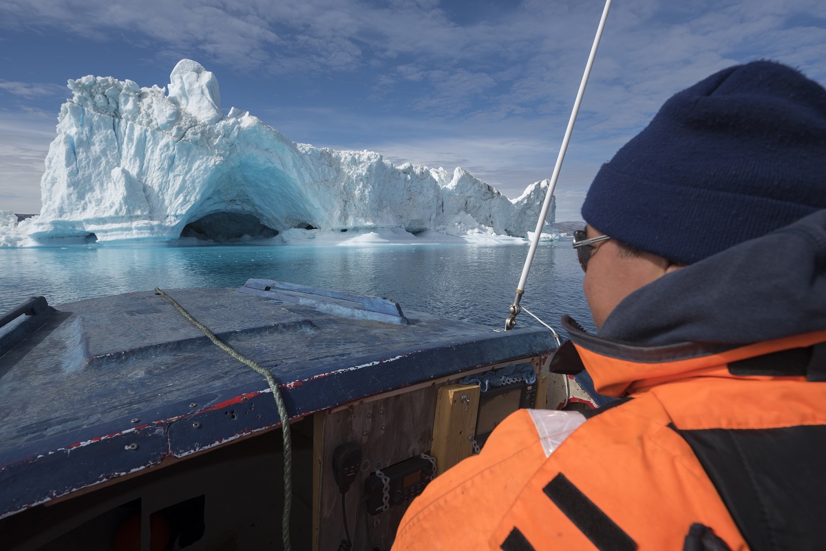 Reiziger op een boottocht kijkt naar de grote ijsbergen in de Sermilik fjord, Groenland