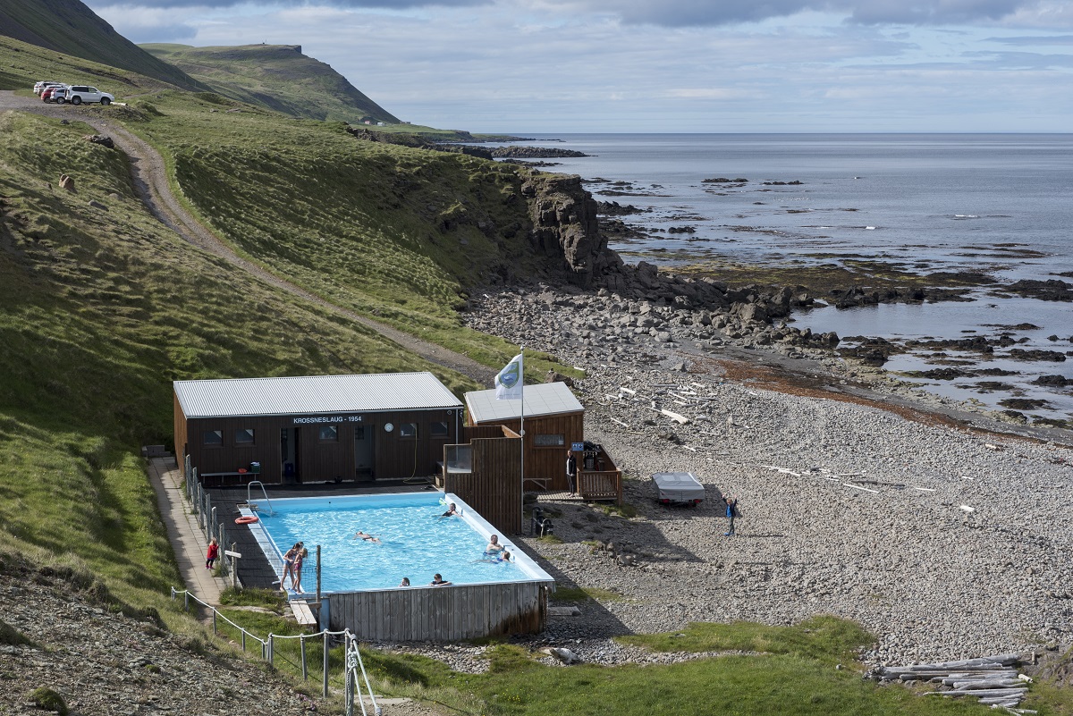 Zwemmers genieten buiten in het warme water van het bad Krossnes, een van de meest afgelegen geothermische baden op de Westfjorden in IJsland.