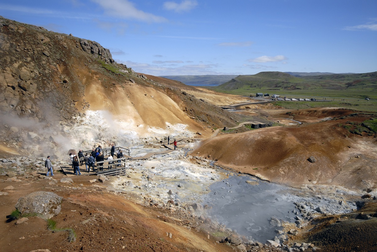Bezoekers bewonderen de kleurrijke, borrelende en pruttelende modderpotjes in het geothermisch gebied bij Krysuvik op Reykjanes, IJsland.