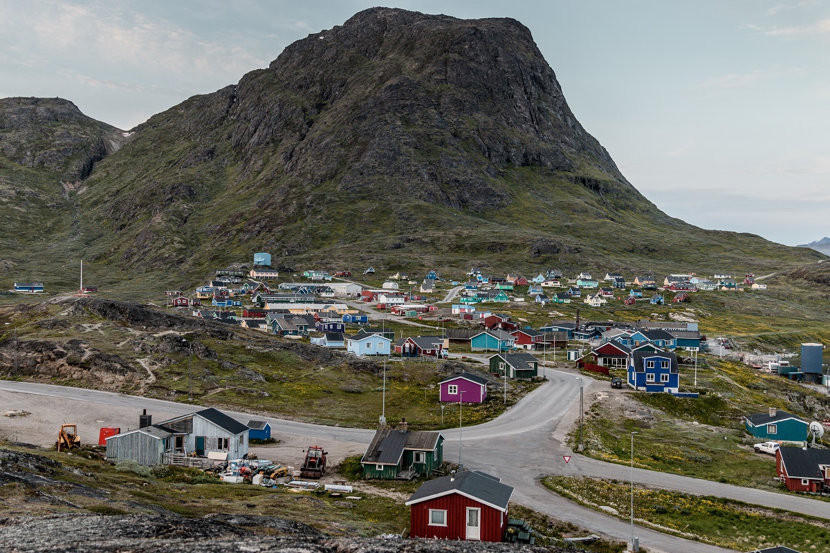 De kleurrijke huizen van het dorpje Narsaq in Zuid Groenland op de glooiende hellingen voor de bergtop.
