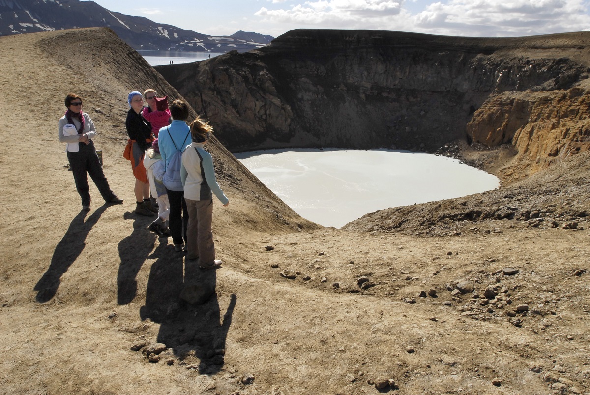 Reizigers staan boven de viti krater bij de vulkaan Aksja in het binnenland van IJsland.