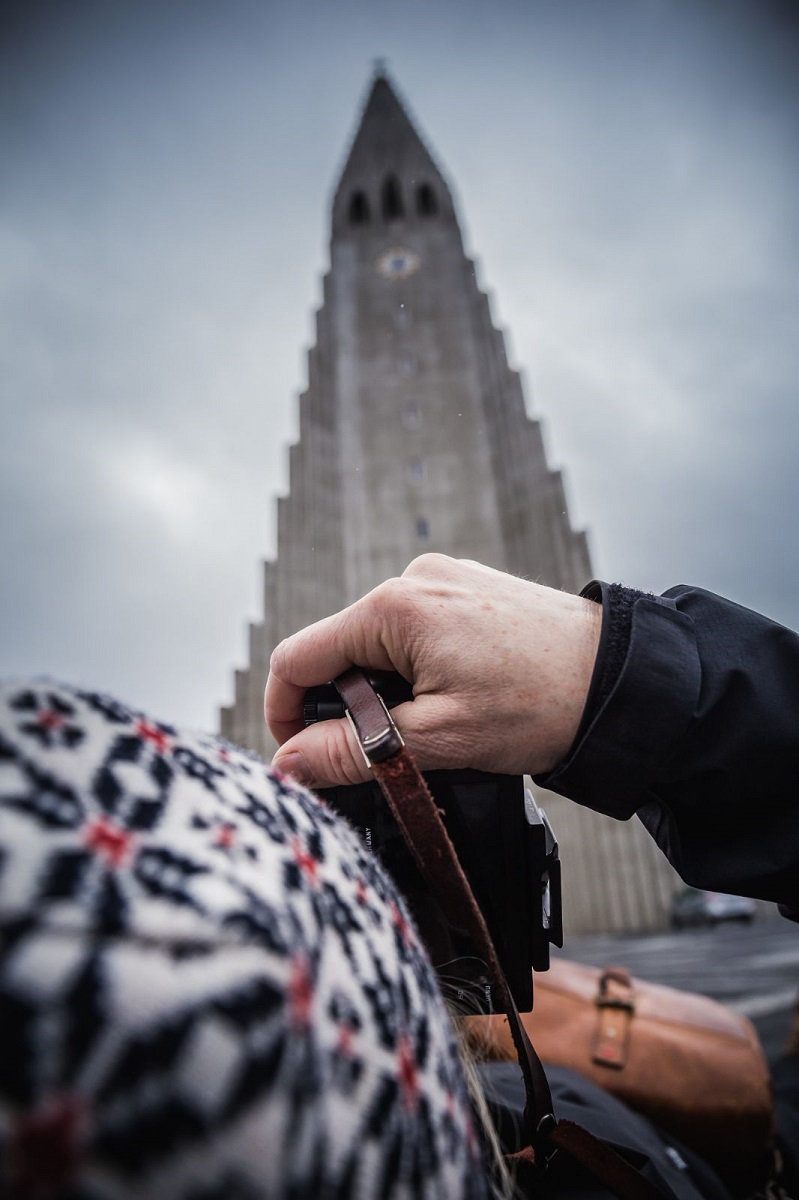 Een toeriste fotografeert de bijzonder Hallgrimskerk in Reykjavik, IJsland.
