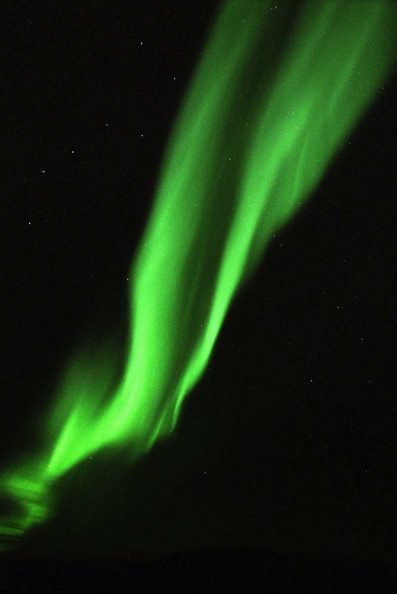 Noorderlicht danst als een groen gordijn boven de IJslandse hemel.