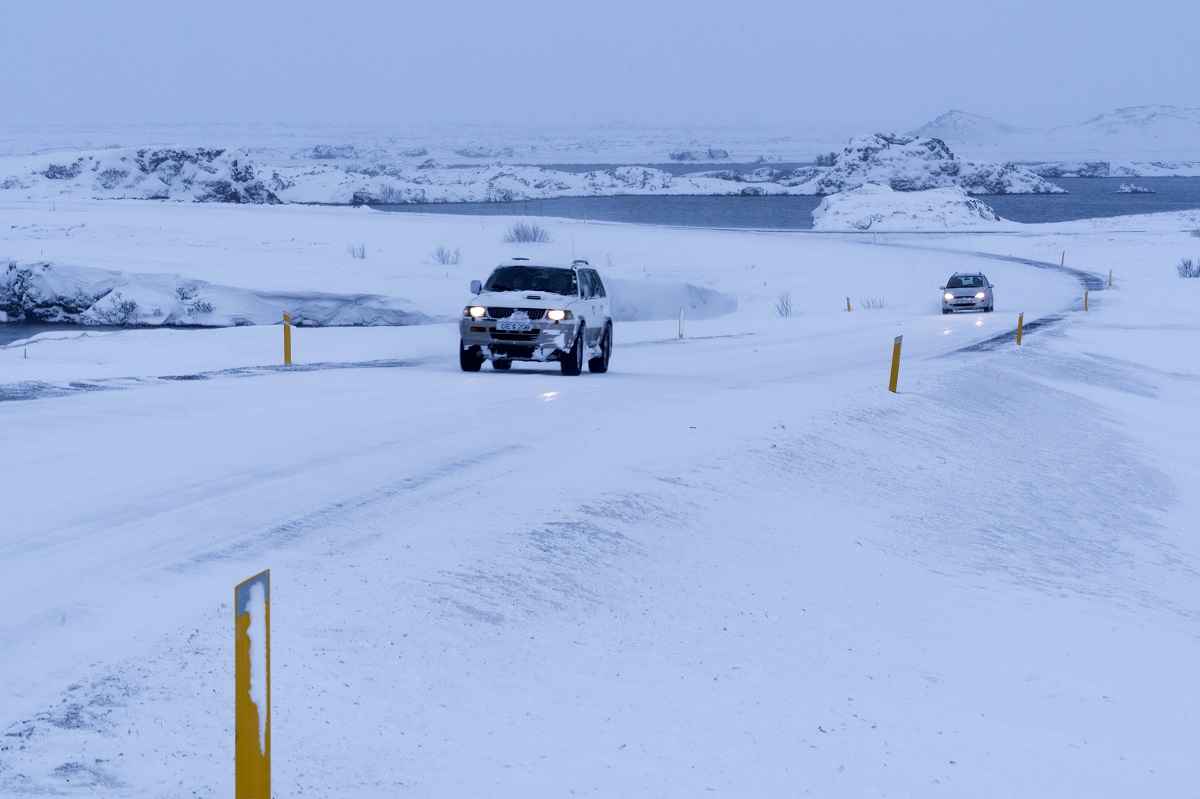 Twee auto's op de besneeuwde weg bij Mývatn in Noord IJsland.