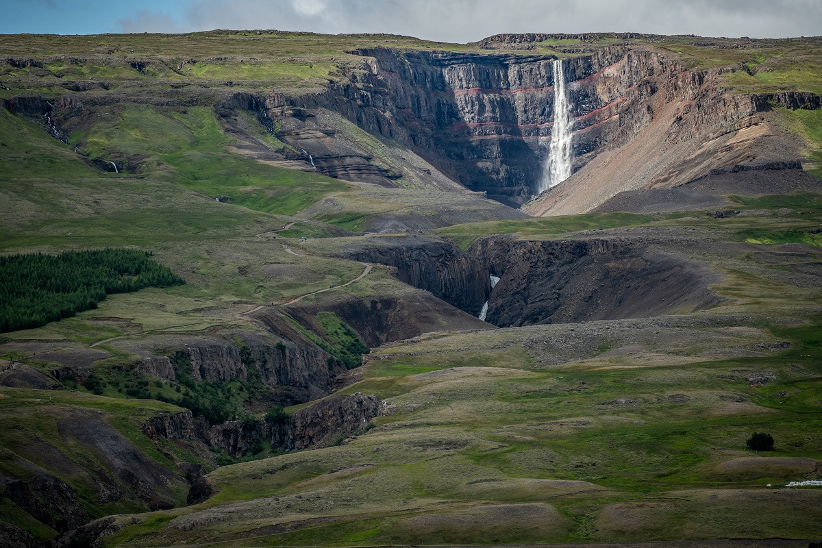 De Hengifoss waterval in oost IJsland zie je in de verte van dit groene landschap.