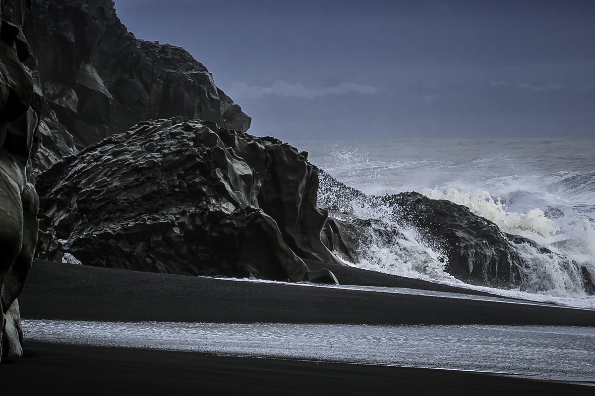 De golven slaan tegen de basaltrotsen bij het zwarte strand van Vik in zuid IJsland.