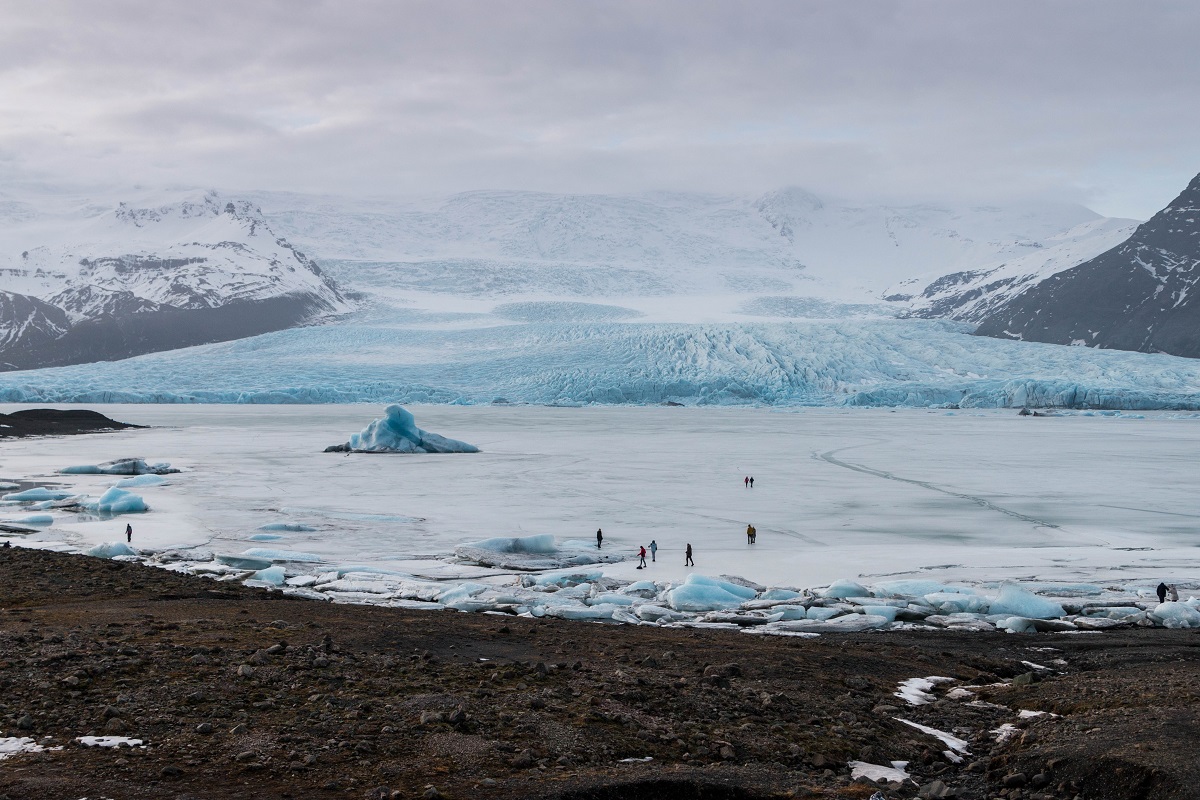 Mensen lopen op het bevroren ijsbergenmeer Fjallsarlon in IJsland.