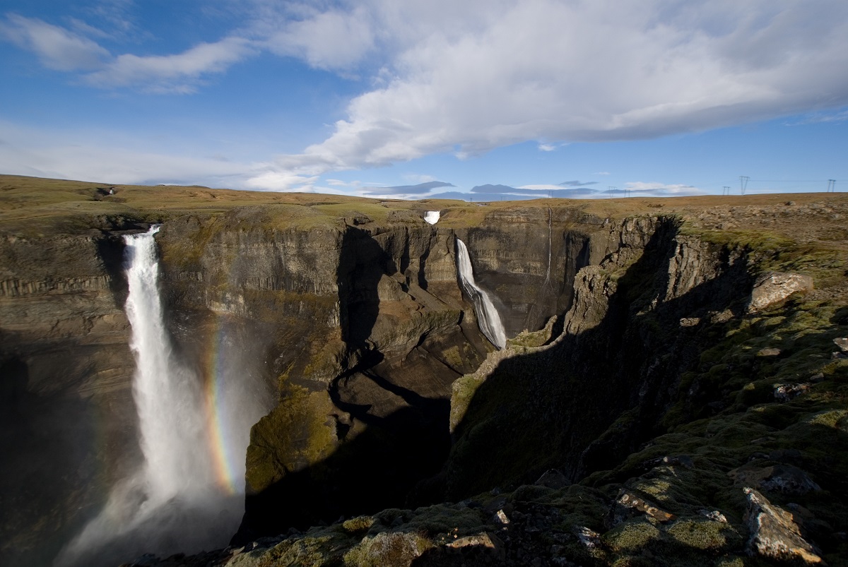 De twee stromen van de waterval Haifoss, in zuid IJsland, storten in de kloof met een regenboog op de voorgrond.