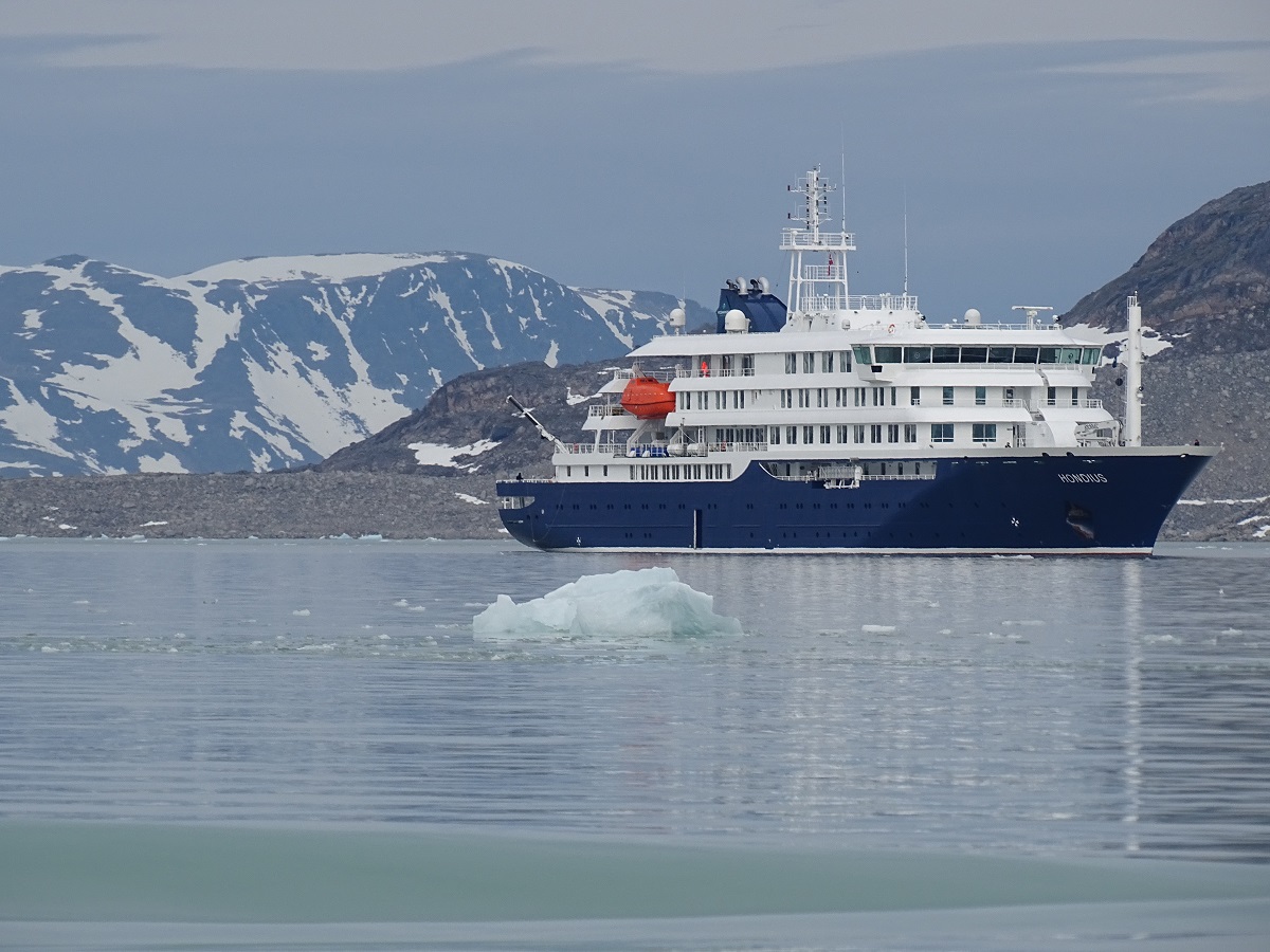 Het expeditie cruiseschip de Hondius met besneeuwde toppen op de achtergrond in Spitsbergen.