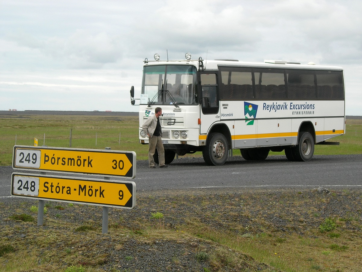 Chauffeur staat naast de hooglanden bus bij de afslag naar Thórsmörk in zuid IJsland.