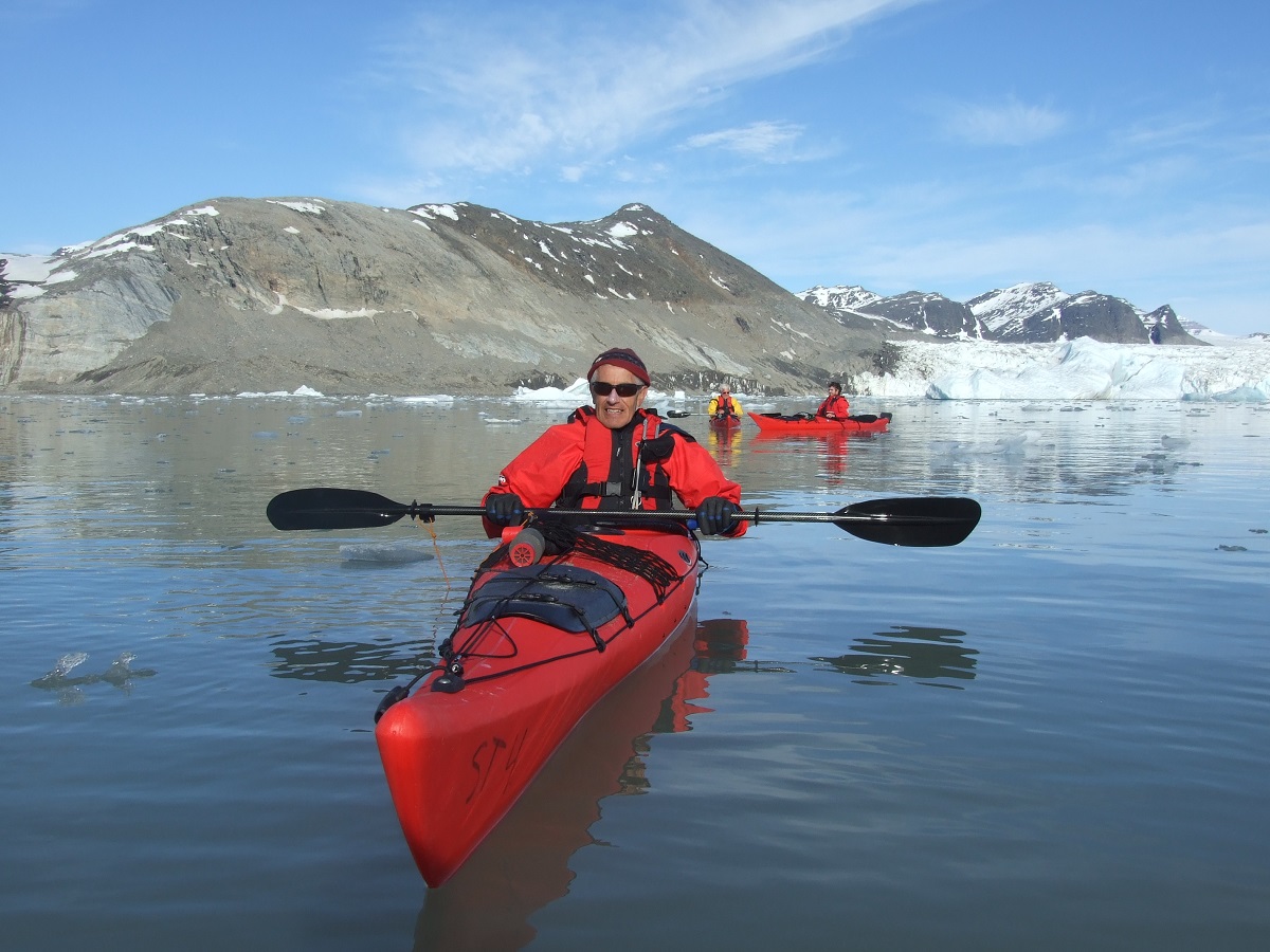 Kajakken, in een rode zee kajak, met de bergen van Spitsbergen en de gletsjer op de achtergrond.