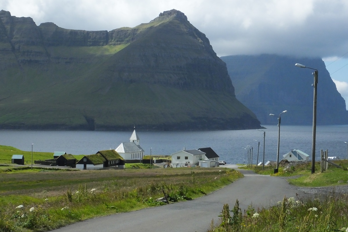 Huisjes in Vidoy, Faroer, met grasdaken en een kerkje met prachtig uitzicht op het fjord.
