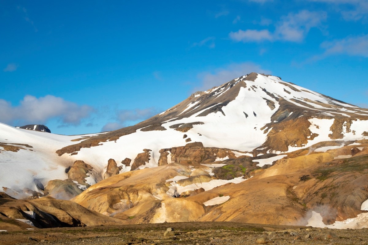 De toppen van de gele Kerlingarfjöll bergen zijn bedekt met een laag witte sneeuw.