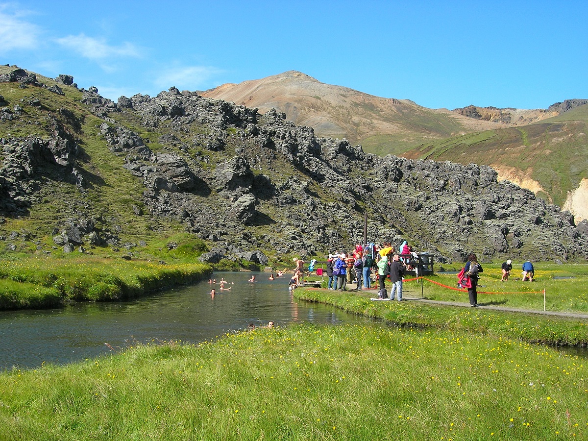Mensen aan het badderen in een natuurbadje bij Landmannalaugar, in de hooglanden van IJsland, in de rivier in het mooie groene landschap met bergen.
