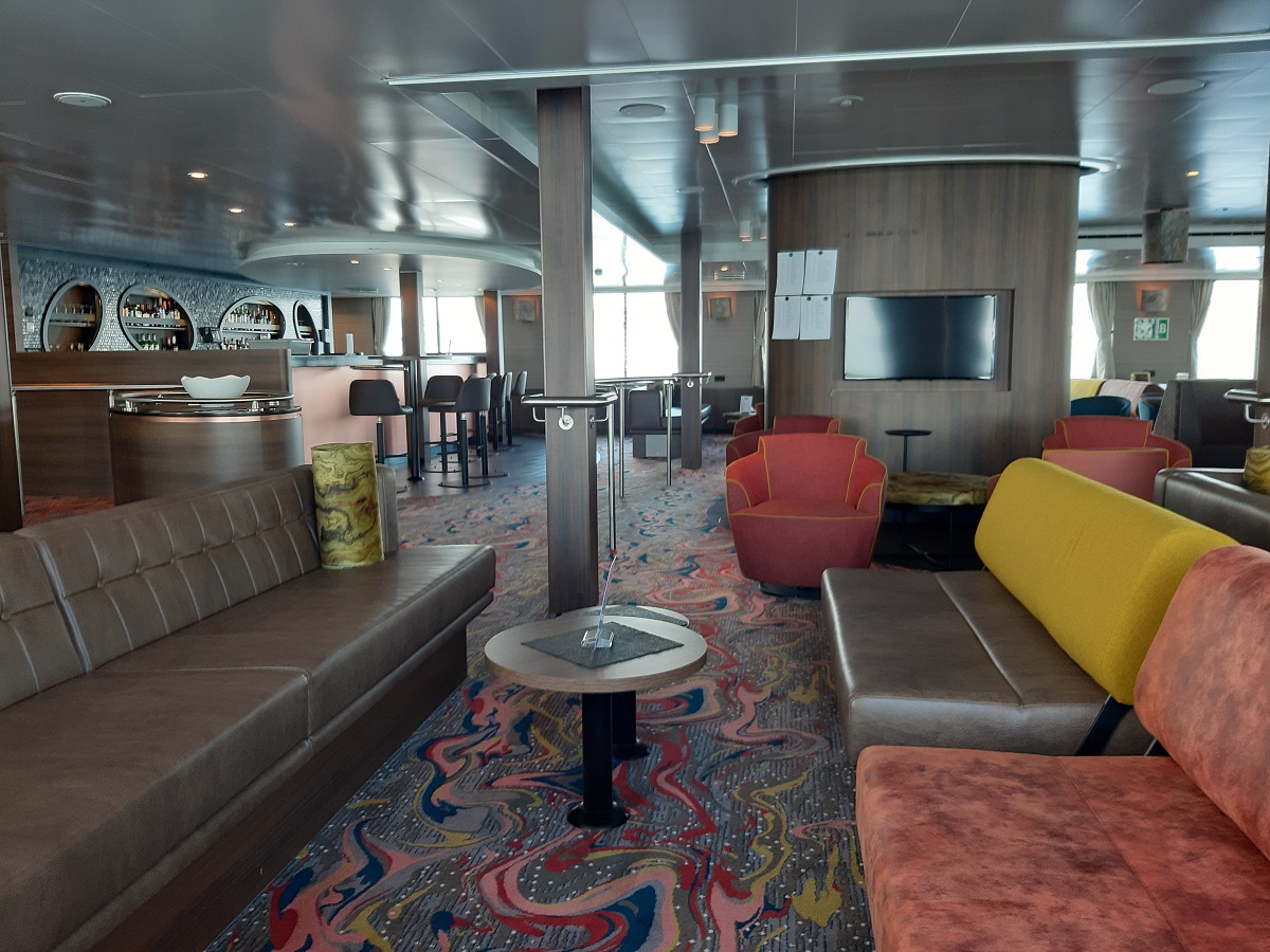 De lounge met oranje en gele banken aan boord van het cruise schip de Hondius.