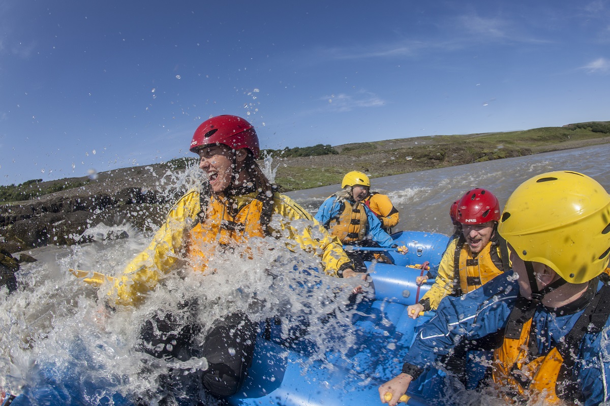 Deze deelnemers worden nat van een splash water tijdens het raften in zuidwest IJsland