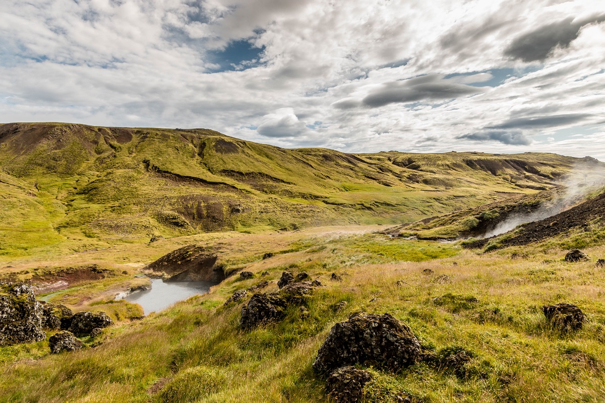 Geothermische warmwater bronnen midden in een groene vallei van Reykjadalur met een mooie wolkenlucht.