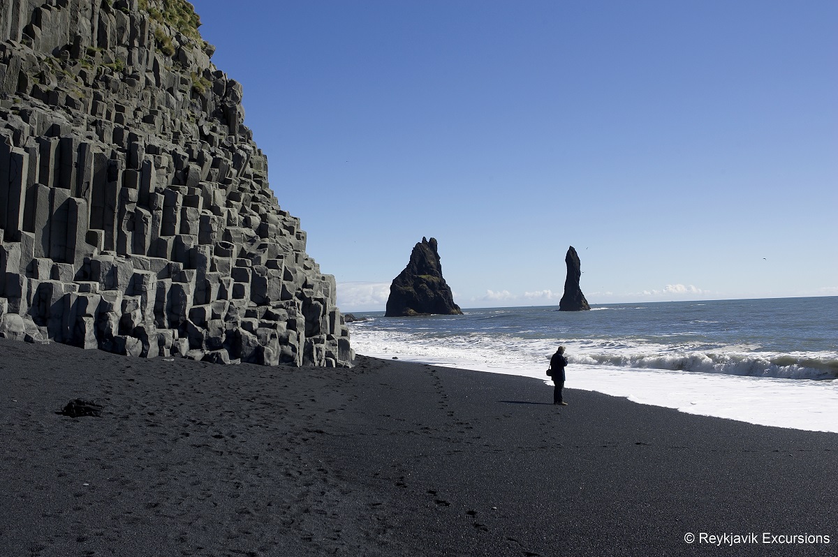 Het zwarte strand Reynisfjara, zuidwest IJsland, met basaltrotsen en rutspunten die in zee staan.