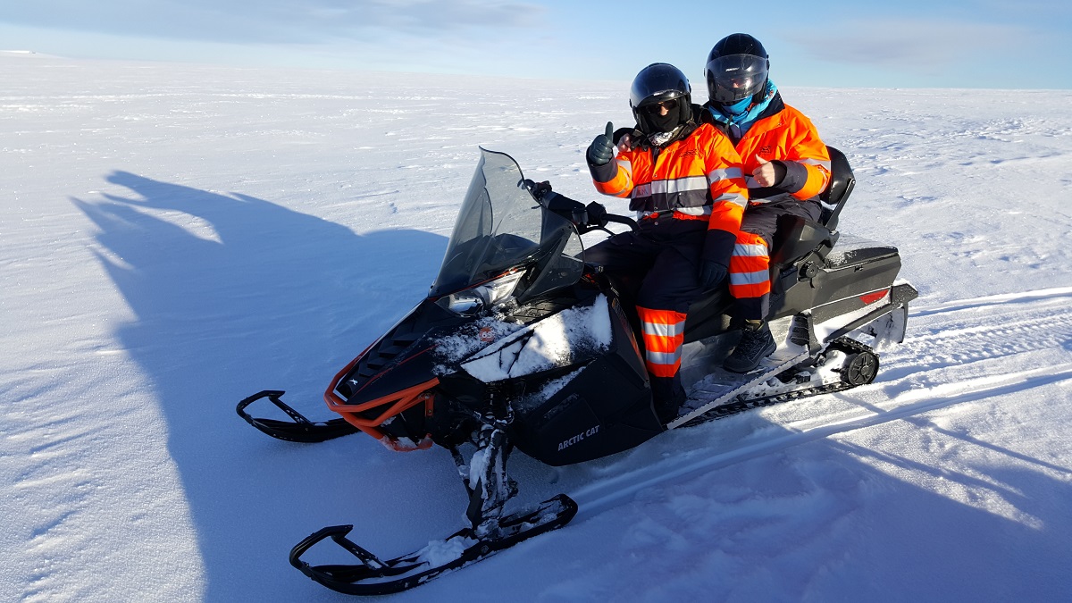 Deze reizigers in oranje pak vinden sneeuwscooteren in IJsland top.