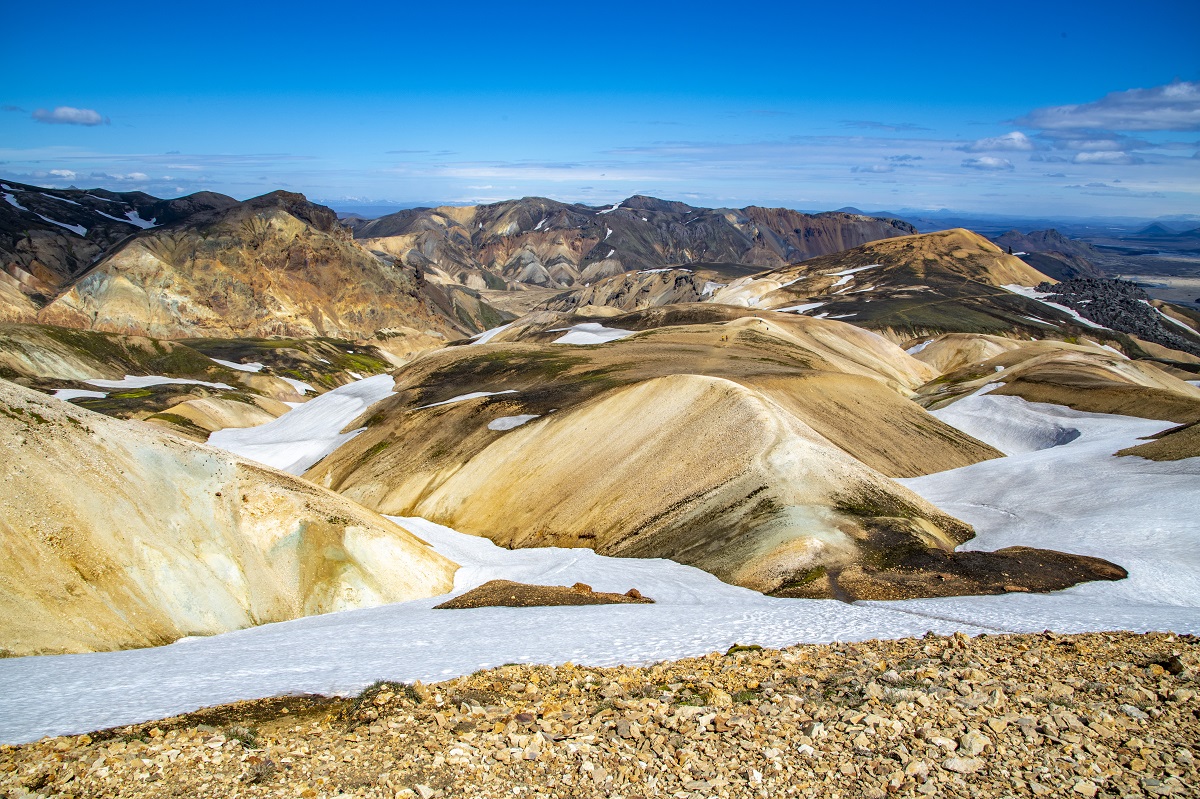 Er ligt sneeuw tussen de kleurrijke heuvels van Landmannalauger, in IJsland, onder een helder blauwe lucht.