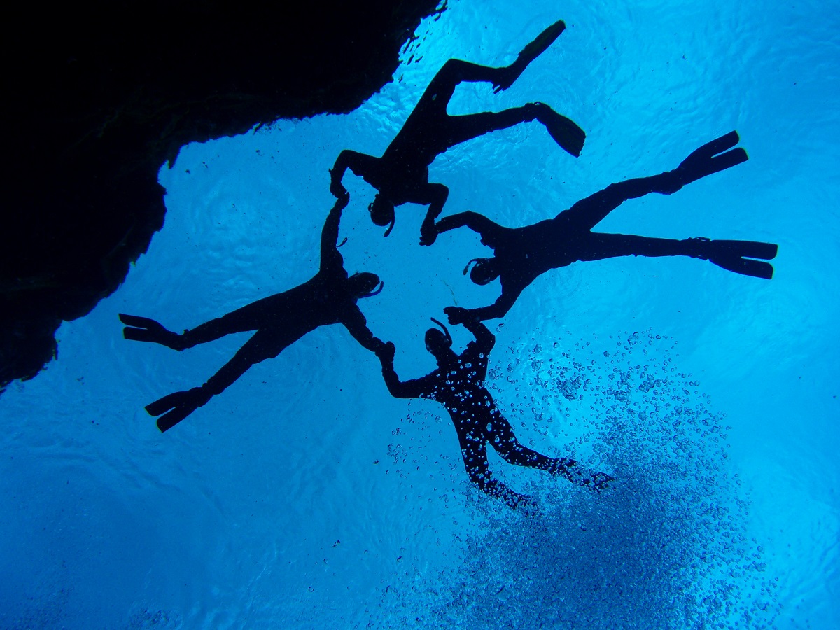 Vier snorkelaars vormen een cirkel in het helder water van de kloof bij Silfra in NP Thingvellir, IJsland.