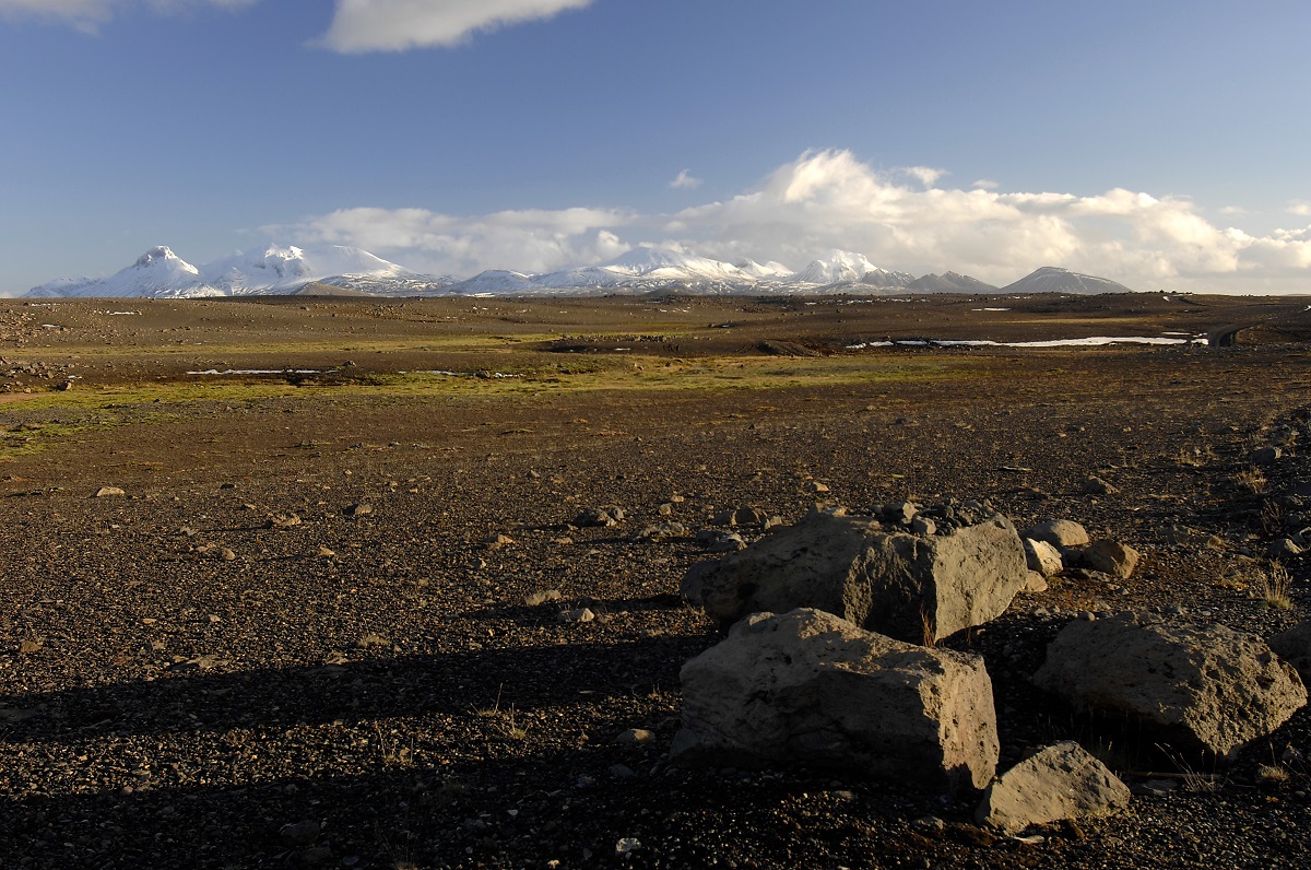 Een kaal landschap van Sprengisandur, in de hooglanden van IJsland met besneeuwde bergen in de verte.