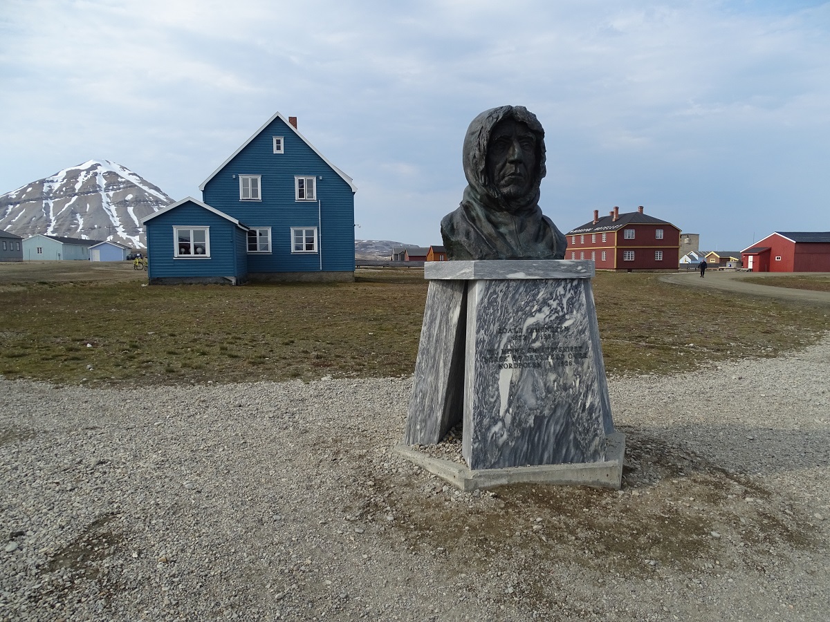 Het standbeeld van Admundsen met blauwe en rode huisjes op de achtergrond in Ny Alesund op Spitsbergen.
