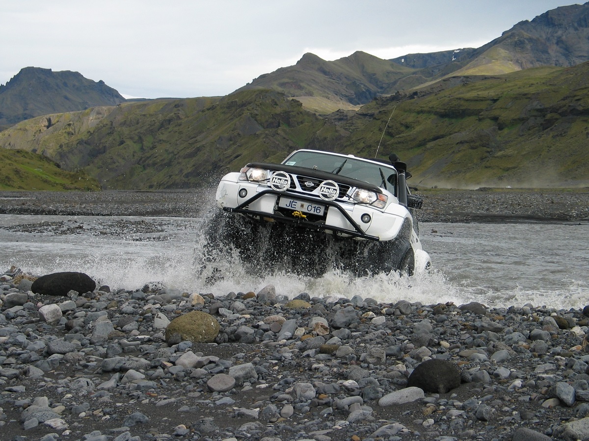 Een witte Nissan superjeep rijdt door de rivier bij de Thórsmörk in de hooglanden van IJsland.