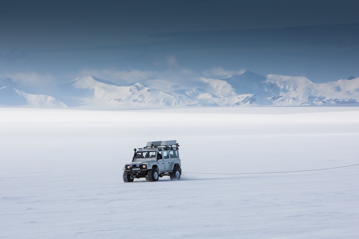 Een stoere Land Rover Defender staat midden op de sneeuw vlakte van de gletsjer Vatnajokull.