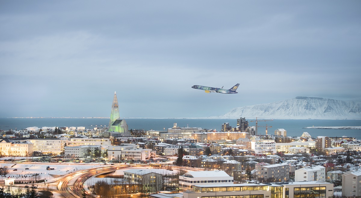 Het vlieguig in de kleuren van het noorderlicht vliegt boven Reykjavik.