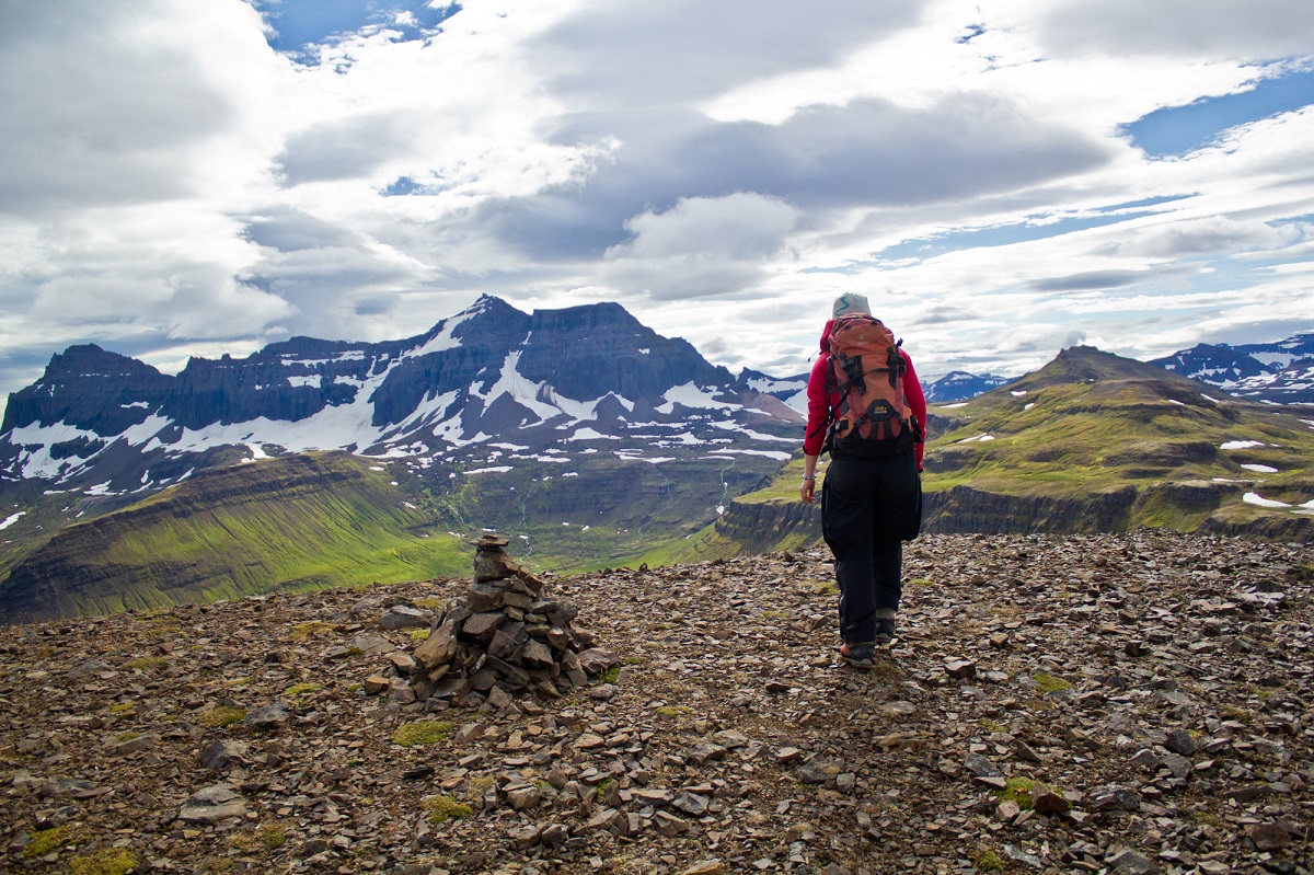 De wandelaar geniet van het uitzicht op de bergen in oost IJsland.