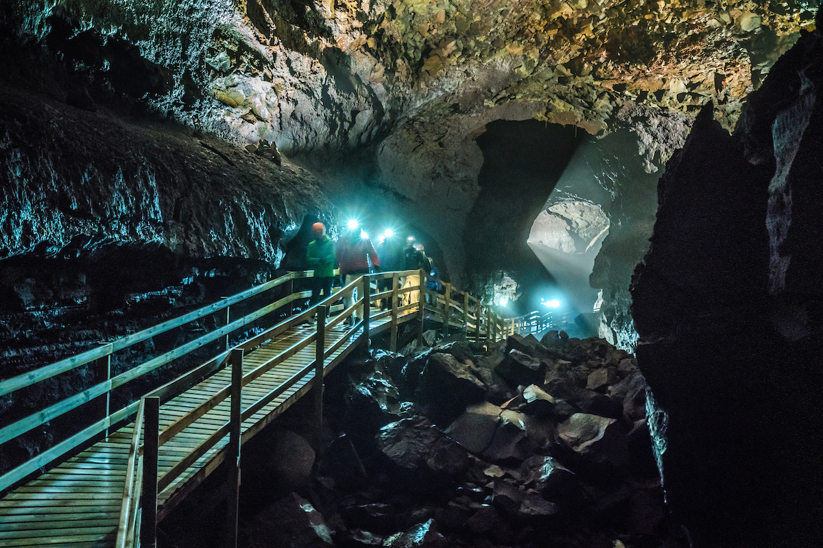 Bezoekers lopen over het houden pad dat in de Vidgelmir grot is aangelegd.