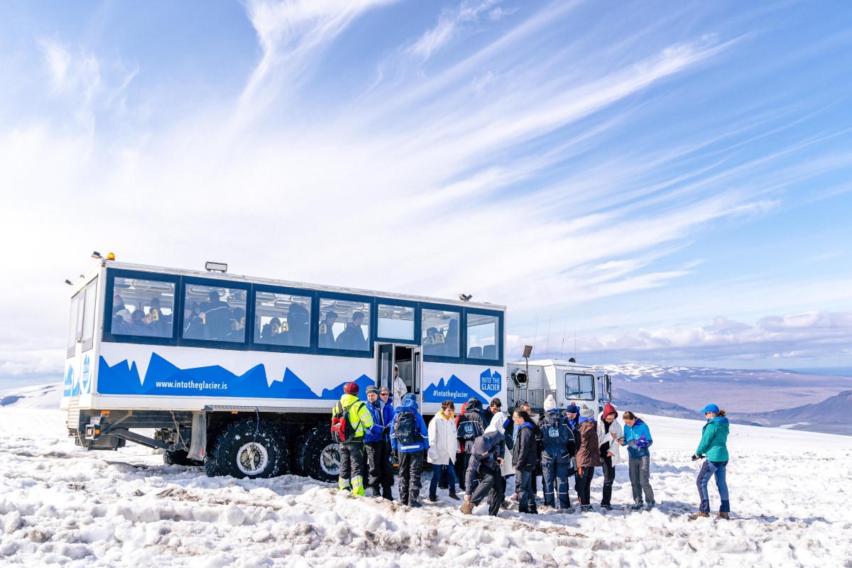 Een groep toeristen staat naar de monstertruck van Into The Glacier op de gletsjer.