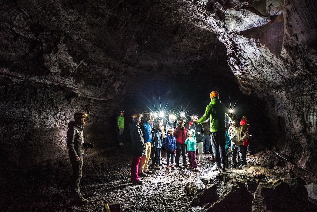 Een groep toeristen krijgen een rondleiding van een gids in de Vidgelmir grot.