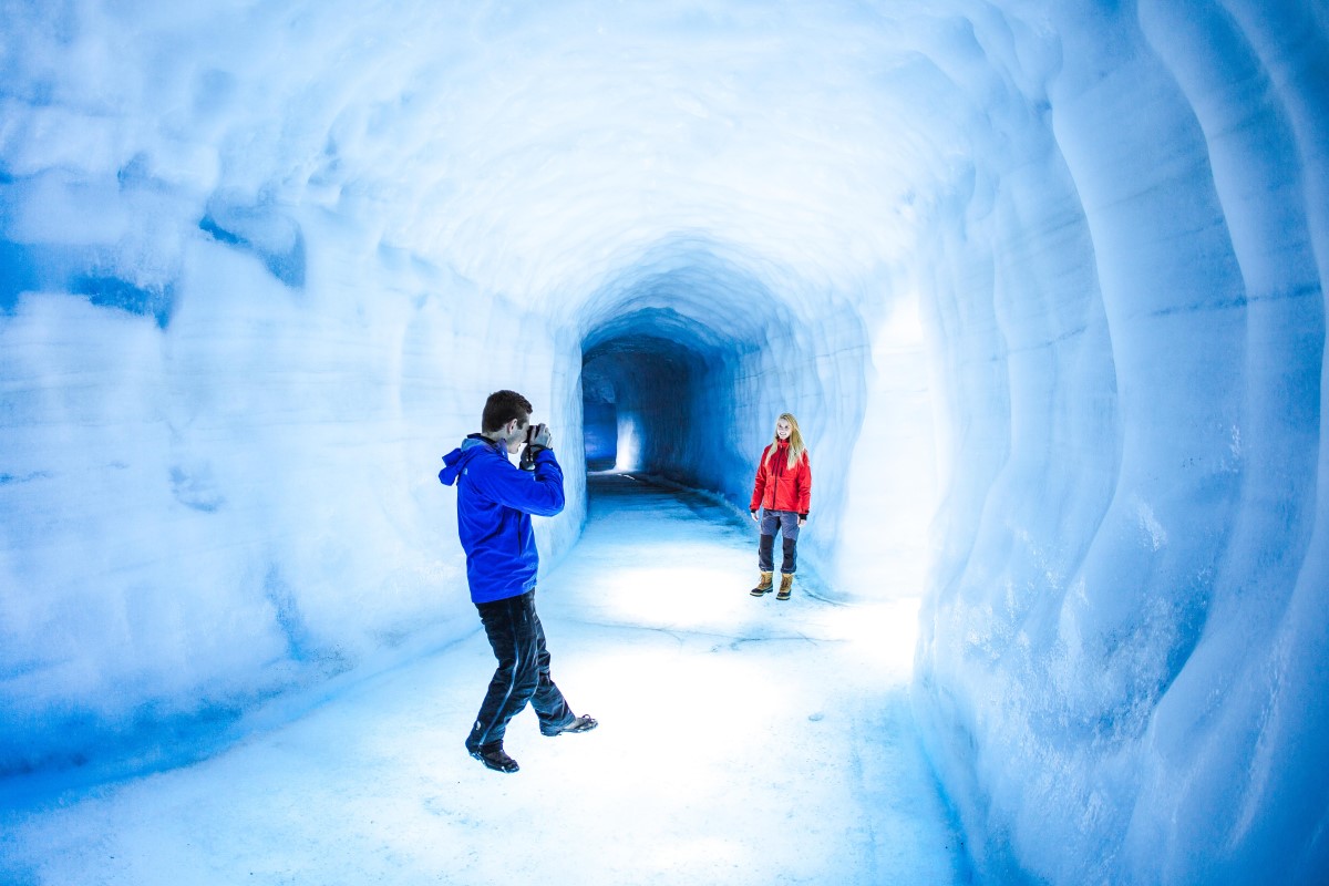 Een fotograaf is aan het fotograferen in de ijstunnel van Into The Glacier.