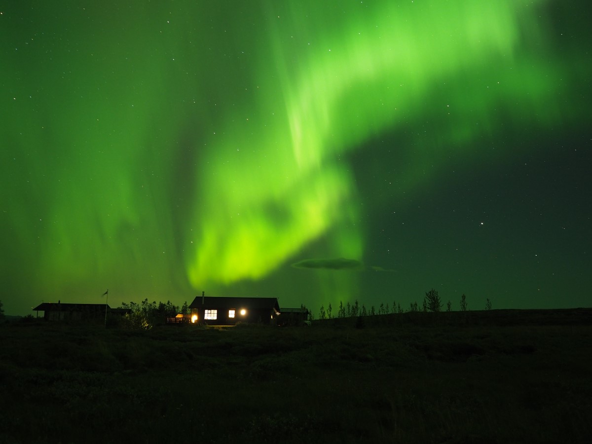 Boven een huisje van Blue View Cabins danst het prachtige, groene noorderlicht.
