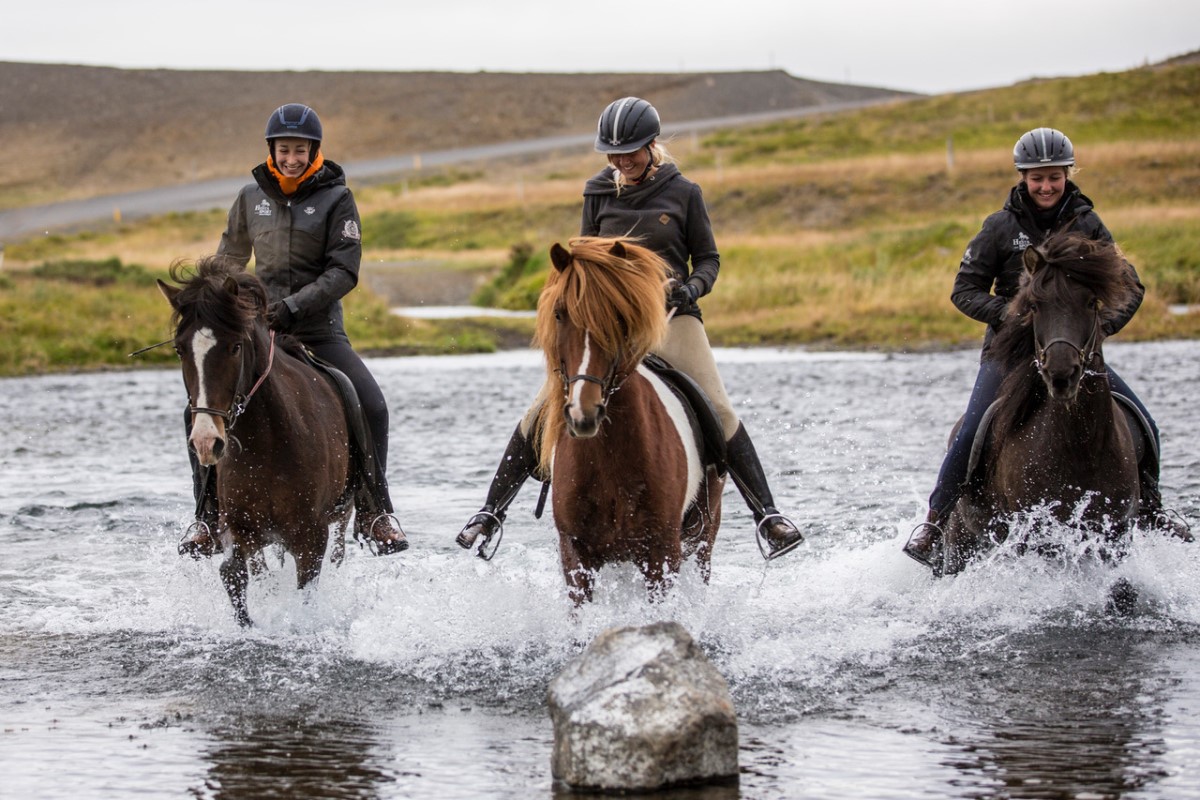 Drie ruiters te paard rijden door de rivier Svarta.