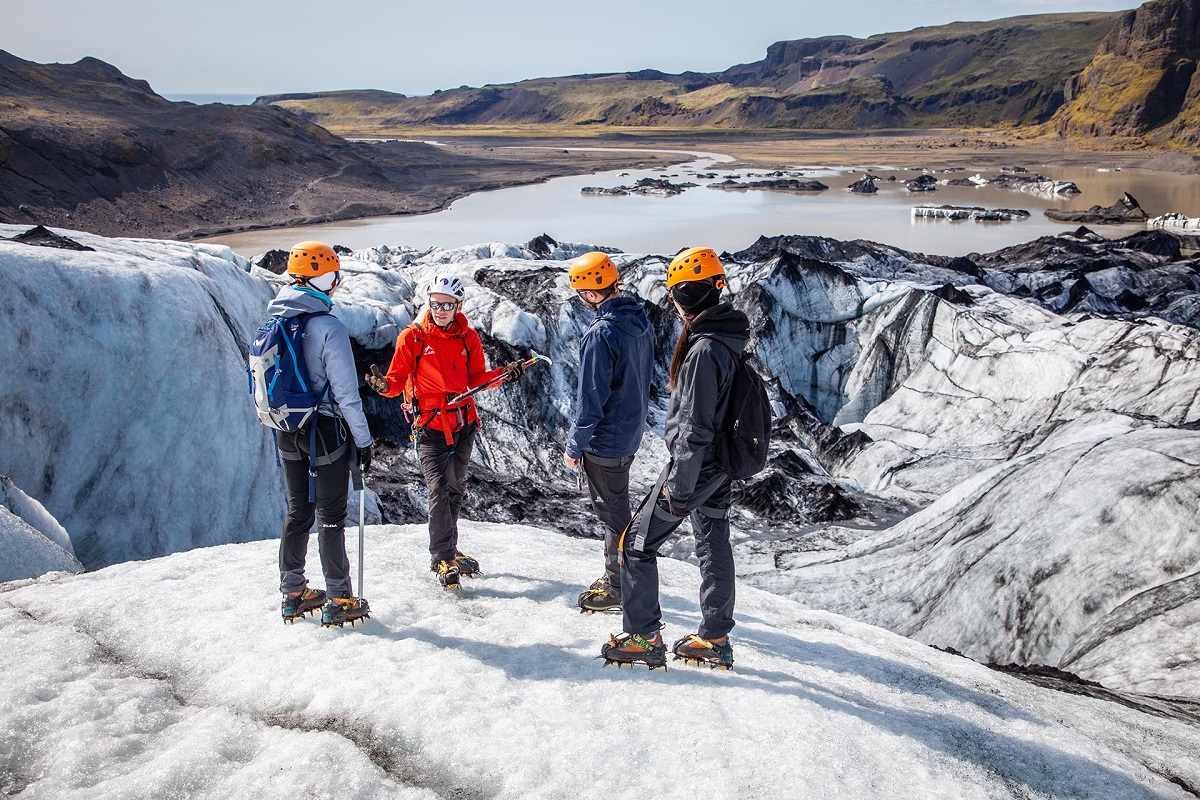 Drie reizigers wandelen met een gids op de Solheimajokull gletsjer.