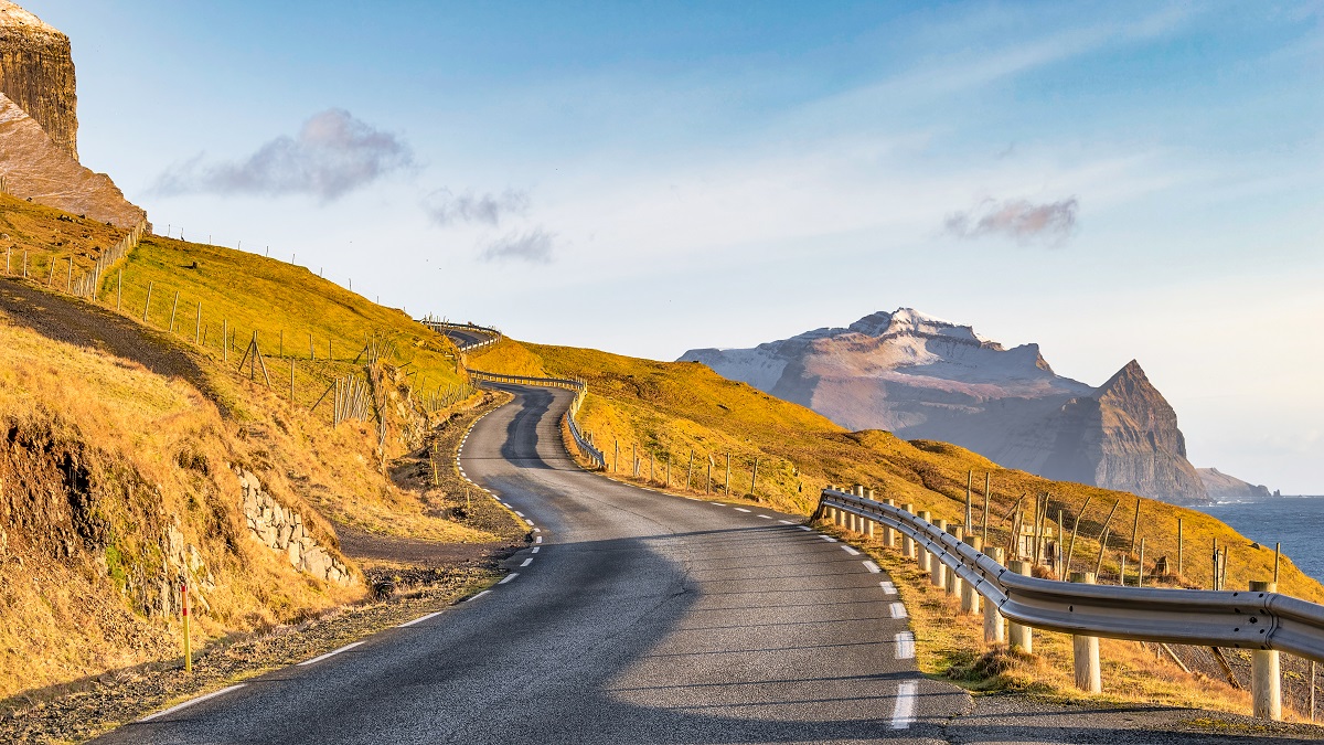 Prachtige kustweg kronkelt door het Faroese landschap met bergen en kliffen.