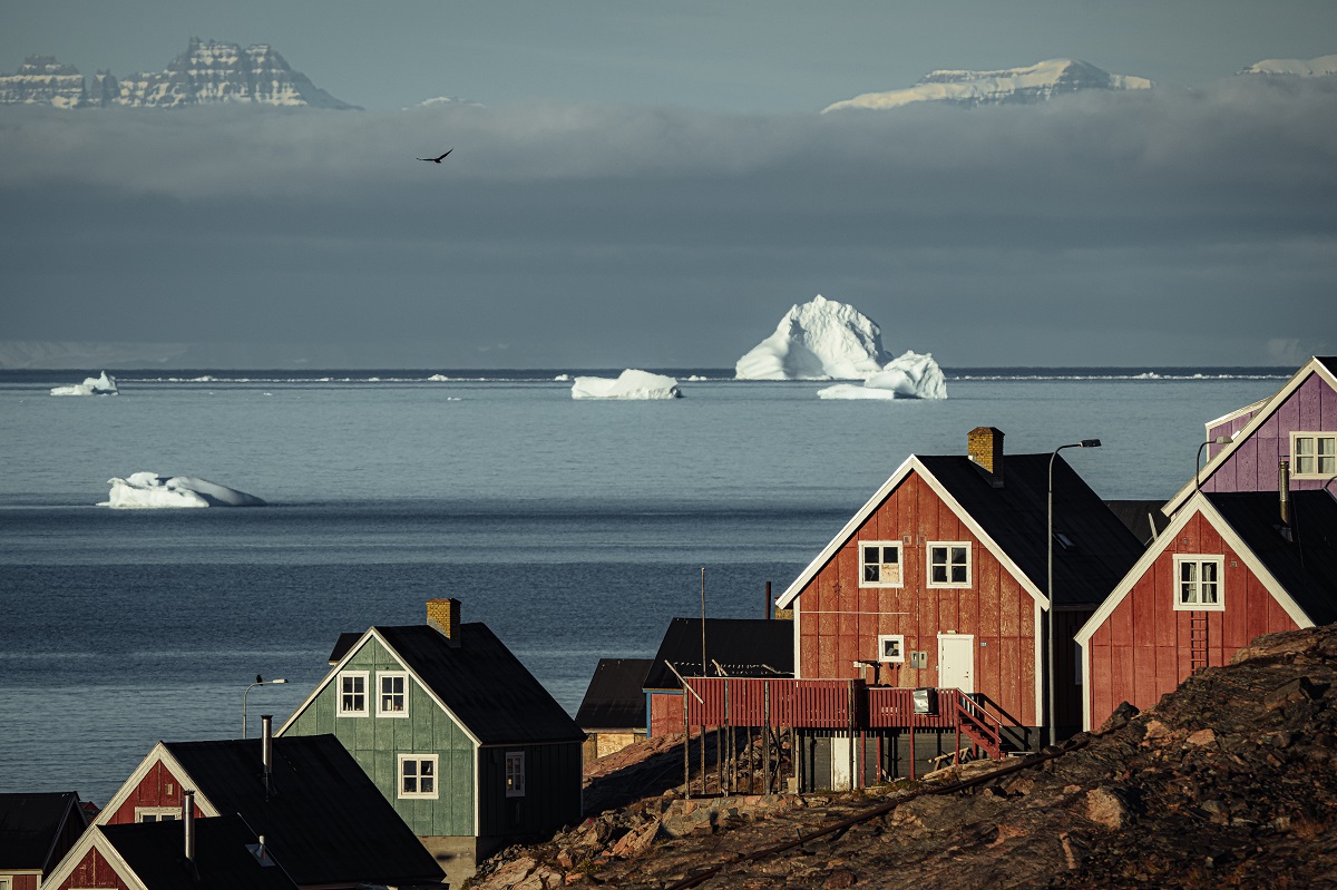 Het dorpje Ittoqqortoormitt met op de achtergrond een ijsberg.
