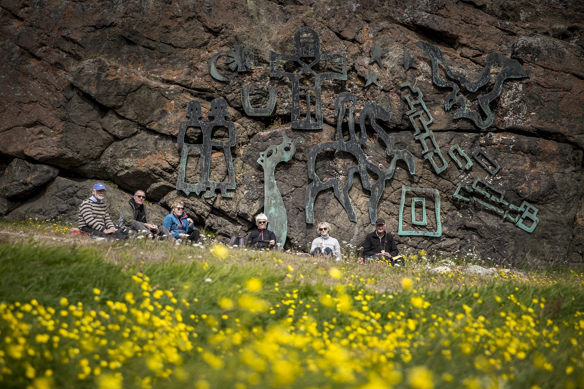 Een groep houdt pauze voor het Sven Havsteen Mikkselsen kunstwerk in Qassiarsuk.