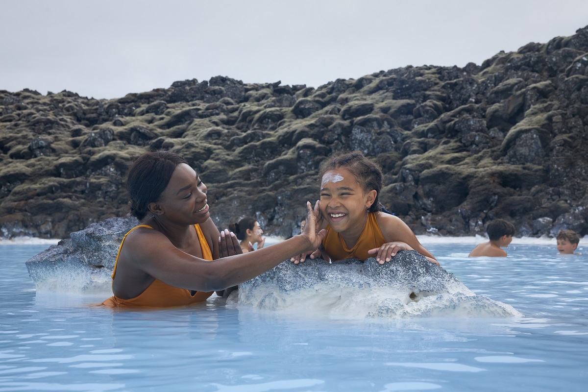 Een vrouw smeert een klei masker op bij het kind en baddert in de Blue Lagoon, een warmwaterbad in Reykjanes IJsland.