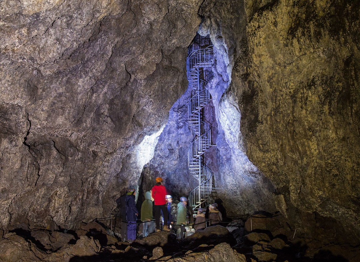 Reizigers dalen via een wenteltrap af in de Vatnshellir lavatunnel.
